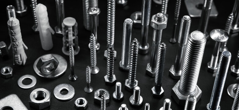 various metal screws, bolts and fasteners on black background