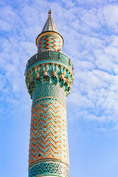The minaret of Green Mosque (Yesil camii) decorated with iznik tiles. Blue sky and clouds at background, vertical shot. Iznik (Nicaea), Bursa region, Turkey