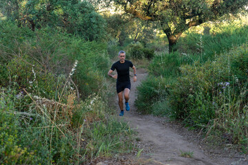 Obraz premium Experienced trail runner with gray hair and sleek black gear, conquering rugged terrain.