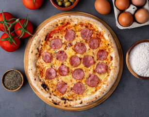 Calabrese sausage style pizza over stone background with tomatoes, olives and oregano