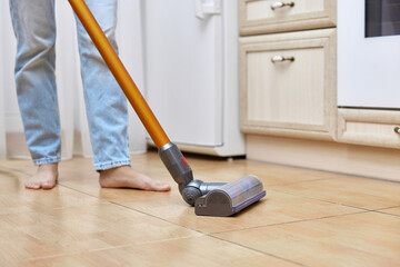 woman uses cordless vacuum cleaner to clean floor.