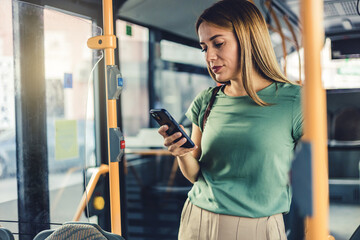 Young woman checking social media on phone in bus. Beautiful girl with long hair using smartphone...