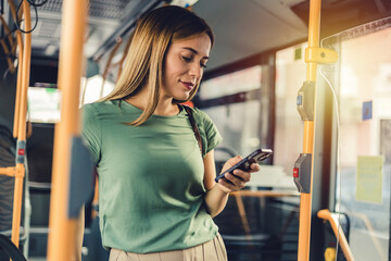 heerful woman with cell phone in public transportation. Smiling young woman with cell phone in...