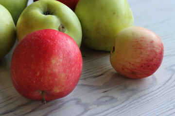 Group of beautiful local green and red apples on the white wooden table. Ripe, fresh, juicy and healthy, harvested in September in the farmer garden. Close up. Top view. Selective focus.