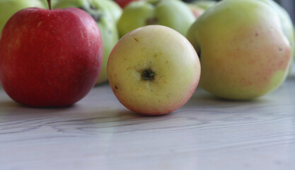 Group of beautiful local green and red apples on the white wooden table. Ripe, fresh, juicy and healthy, harvested in September in the farmer garden. Close up. Side view. Selective focus.