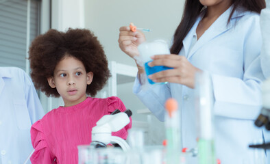 In the science classroom, an Asian child scientist experimenting with scientific formulas with chemicals