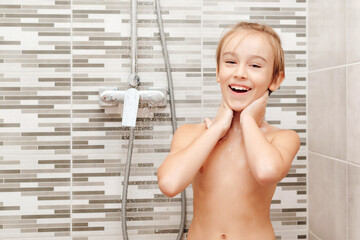 Happy boy having a shower in bathroom.