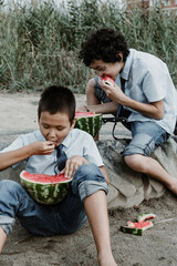 Little boys playing while eating watermelon on beach
