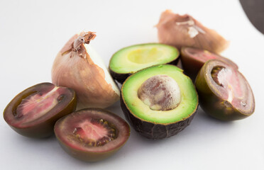 Vegetables black tomatoes, avocado and onions on white background