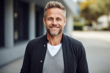 Fototapeta premium Joyful mature man with beard smiling and looking at camera in city
