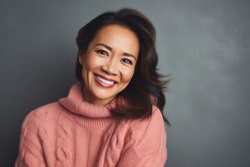 Fototapeta premium Delighted woman with a bright red sweater and a joyful smile on gray background