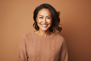Cheerful woman with curly hair smiling and looking at camera on colored background