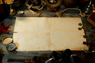 Sheet of paper on rustic wood table with vintage marine objects. Treasure island background. Hold of a ship.