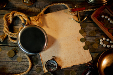 Treasure island concept on a wooden table background. Black flask on sailor or pirate table between different marine atributes and treasure