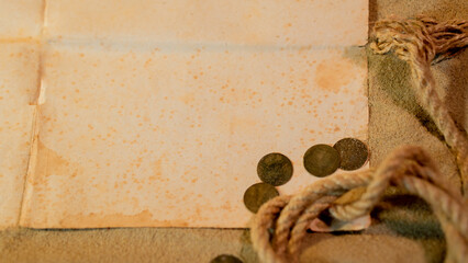 Treasure island theme.  Vintage paper and rope with coins on sand. 