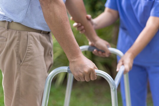 Senior man exercise walking in backyard with caregiver.