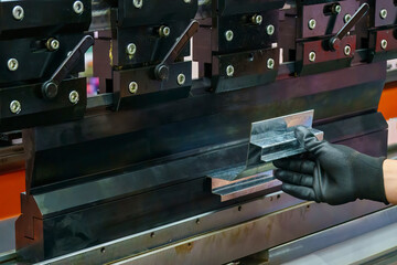 Close up the bending machine operator hold the sheet metal parts and  wear safety  rubber glove.