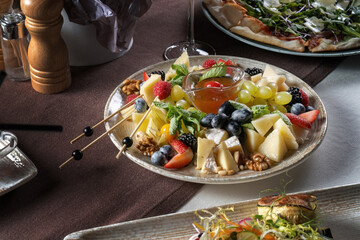 Cheese platter: variety of cheeses with fruits, nuts and berries. In the background are other...