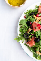 Rocket (arugula) and lamb's lettuce salad with grapefruit, pomegranate seeds, black olives, capers, walnuts, and mustard vinaigrette dressing