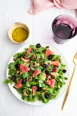 Rocket (arugula) and lamb's lettuce salad with grapefruit, pomegranate seeds, black olives, capers, walnuts, and mustard vinaigrette dressing