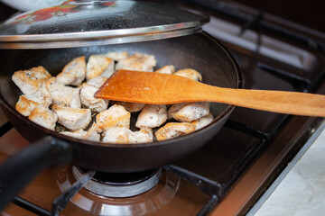 chicken breasts meat only on frying pan and wooden spatula and glass lid, domestic healthy cuisine in real life situation.