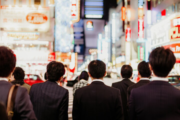 Japanese corporative business people in suits, waiting in rush hour on crossroad in Shinjuku...