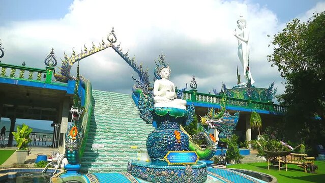 Thailand Chonburi 2023 september 9 Tourist holding a rainbow umbrella at Wat kho pra kru temple white monk sitting and dark gray cloud