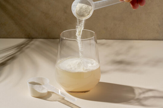 Protein powder added with measuring scoop in a glass of water. Nutrition and food supplement