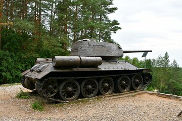 Fototapeta na wymiar A close up on a massive tank on wheels with its long barrel used for shooting pointing towards the bottom of a tall hill standing in the middle of a forest or moor spotted on a Polish countryside