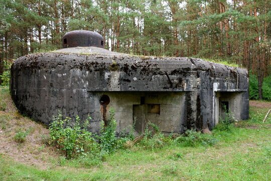 A close up on a massive concrete bunker or bomb shelter located in the middle of a vast forest or moor with some metal observation or shooting towers attached to it seen on a cloudy autumn day