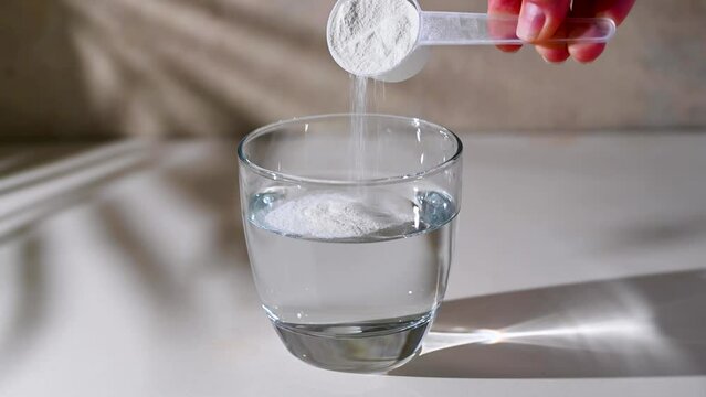 Protein powder added with measuring scoop in a glass of water. Nutrition and food supplement