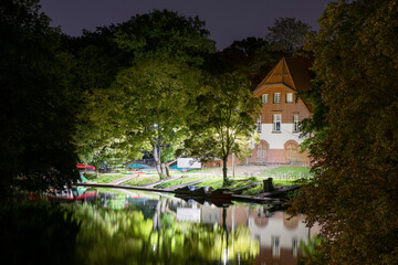 Night park and lake in the old town. the light of lanterns and glare on the water.