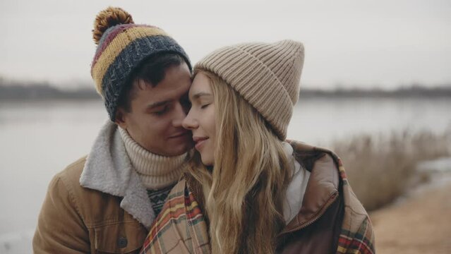 Cheerful smiling couple kissing on nature closeup. Portrait of happy affectionate lovers enjoy romantic date in park. Positive sensual pair feeling love hapiness together. Romance relationship concept