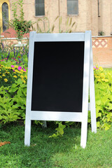 Blank copy space wedding welcome sign mockup in a park with flowers and plants.