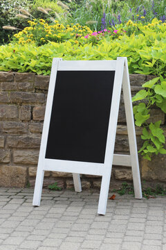 Blank copy space wedding welcome sign mockup in a park with flowers and plants.