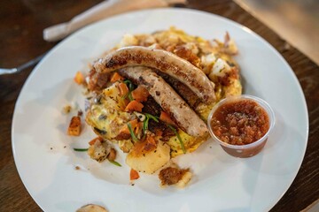 delicious platter of breakfast food including eggs, sausage, potatoes, veggies, and salsa at a restaurant