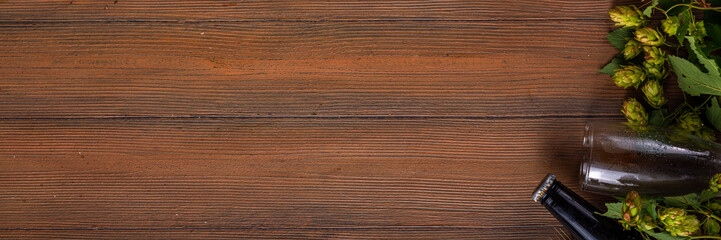 Beer bottle and glass with hop cones, Fresh craft beer and ingredients, copy space on wooden background