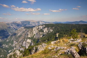 Hiker in the mountains look to the distance. Tara Canyon in Montenegro . - obrazy, fototapety, plakaty