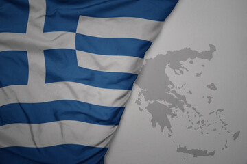 big waving national colorful flag and map of greece on the gray background.