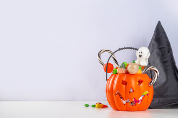 Pumpkin jack-o-lantern bucket full with candies. Children Halloween trick or treat party...