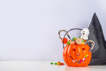 Pumpkin jack-o-lantern bucket full with candies. Children Halloween trick or treat party...
