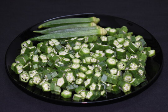 fresh chopped cut sliced lady finger vegetable black plate background isolated
