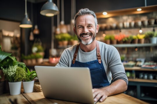 Portrait of smiling business owner makes orders at laptop in his store