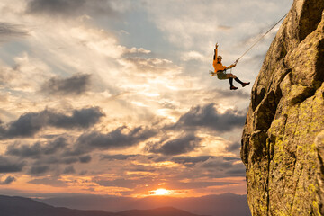 Woman climbing at sunset on mountain golden colors, feeling security and confidence