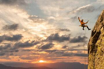 Woman climbing at sunset on mountain golden colors, feeling security and confidence