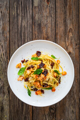 Linguine with salmon and sun dried tomatoes on wooden table

