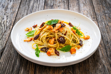 Linguine with salmon and sun dried tomatoes on wooden table
