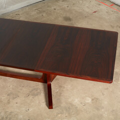 Exquisite rosewood splay-leg dining table. Rich red wooden furniture. Close-up detail photograph.