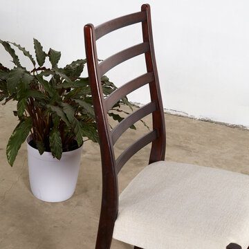Elegant Mid-Century Modern rosewood dining chair. Vintage dark wood ladderback chair. Interior photograph. Close-up detail.