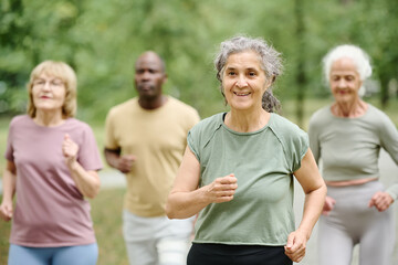 Senior woman running with her friends outdoors in the park
